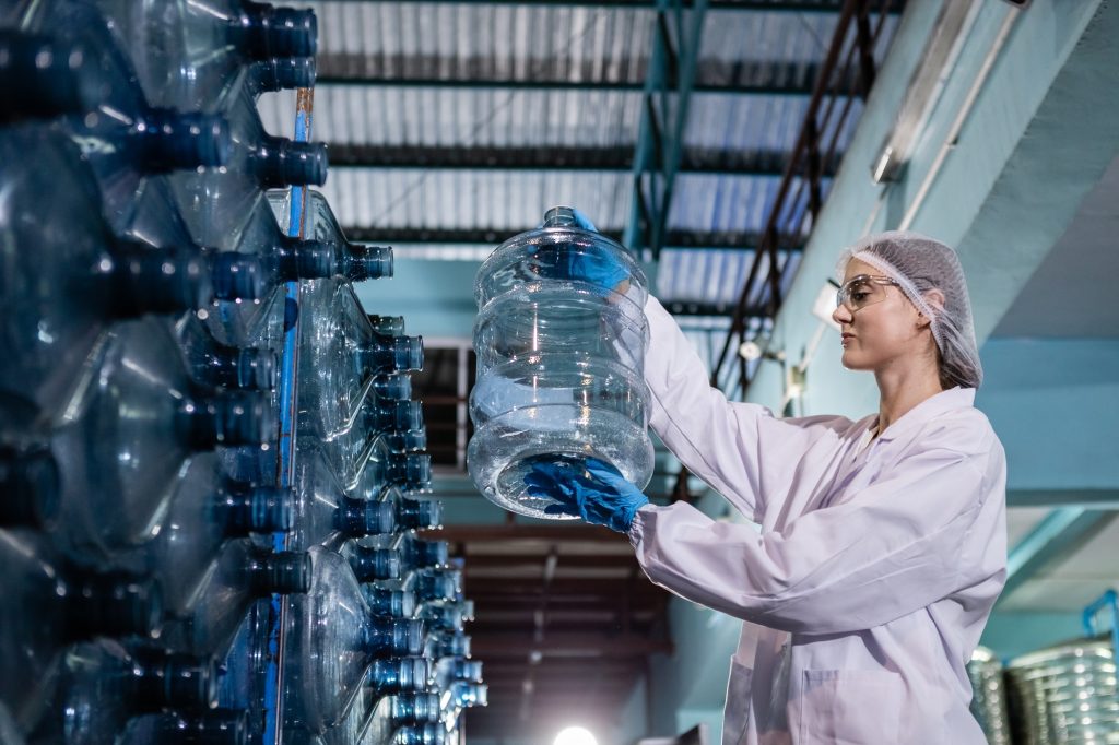 Female worker holding checking quality of large drinking water tanks before process
