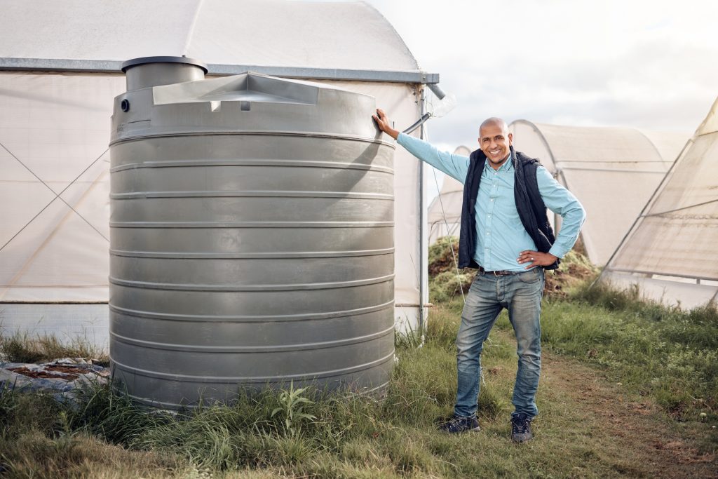 Man, portrait and water tank in farming liquid or soil hydration for vegetables, food and crops gro